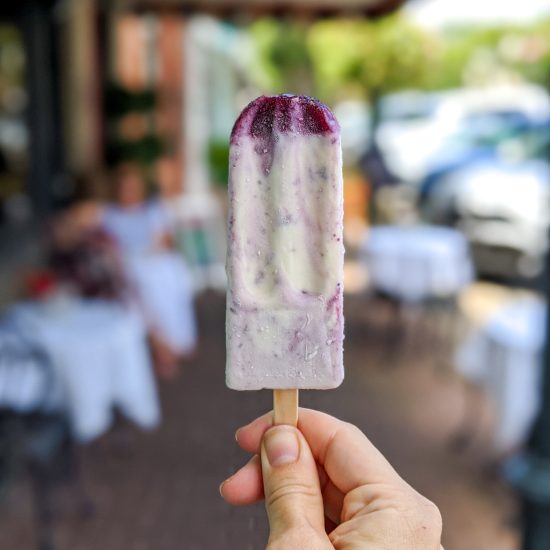 An ice cream pop in the foreground and a blurry street scene in the back