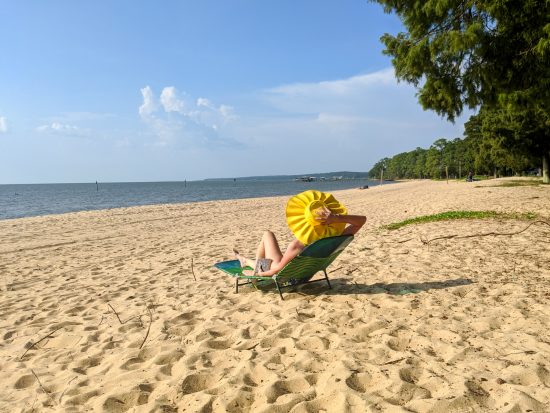 A sunbather in a yellow hat on a golden sand beach.