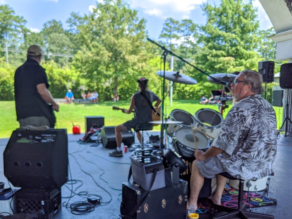 A four piece band performs at an outdoor amphitheater
