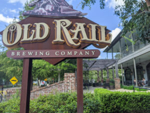 A sign for Old Rail Brewery stands in front of a brewpub.