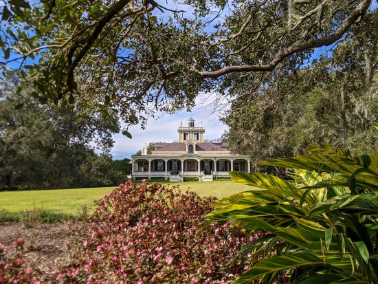 A mansion sits on a broad field framed by live oaks and flowers on a weekend getaway in New Iberia.